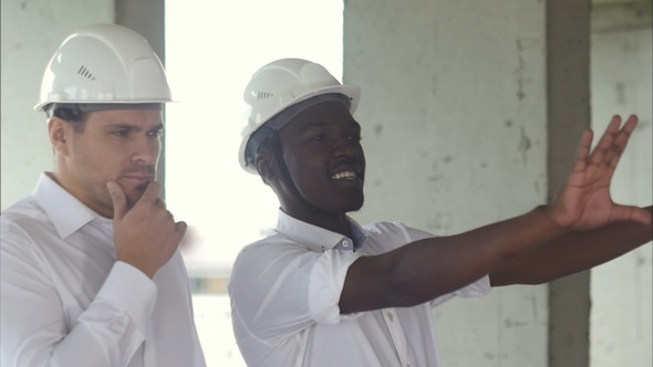 Cheerful african construction worker and manager talking