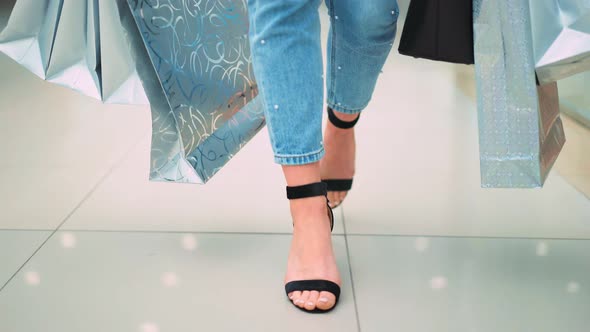 Closeup of Female Legs in Stylish Black Shoes with Shopping Bags Walking in the Mall