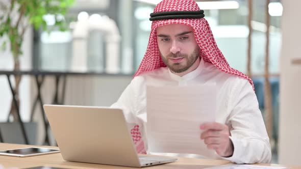 Serious Businessman Working on Laptop with Documents in Office 