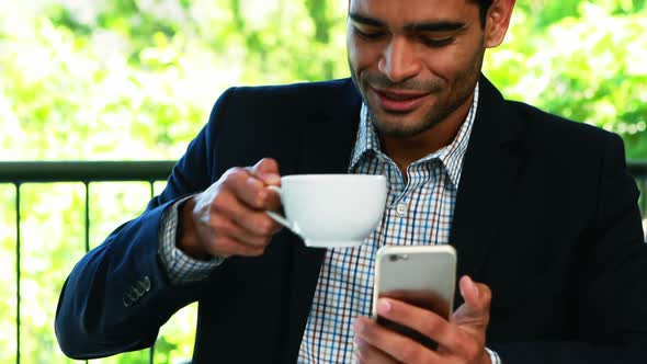 Businessman using mobile phone while having coffee 4k