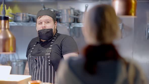 Portrait of Chubby Caucasian Chef in Apron and Cook Hat Listening Blurred Manager Scolding Employee