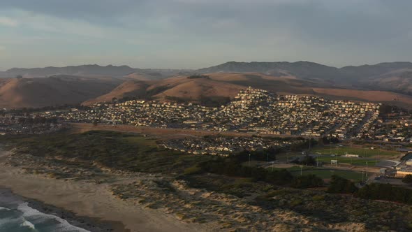 aerial view of large sand dunes during sunset with a large residential area full of homes and soccer