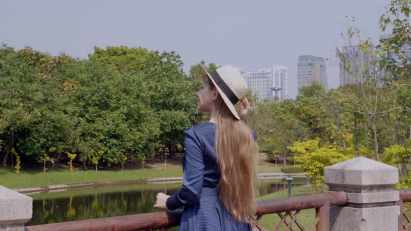 Young Smiling Woman with Long Hair Relax on River Bridge in City Park