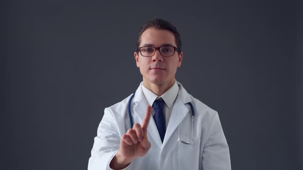 Studio portrait of young professional medical doctor standing over grey background