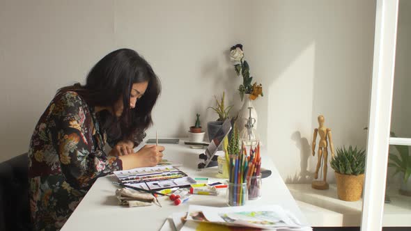 Artist painting in her studio while using a digital tablet