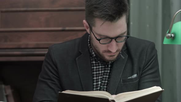 Young Academic in Glasses Attentively Reading a Book