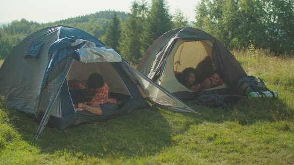 Positive Diverse Multiethnic Backpackers Enjoying Leisure at Campsite During Mountain Hiking