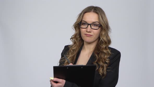 Female Office Worker Holding Clipboard Looks Around and Makes Notes Over Gray Background