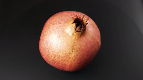 Bright Ripe Pomegranate Rotating Against Black Background