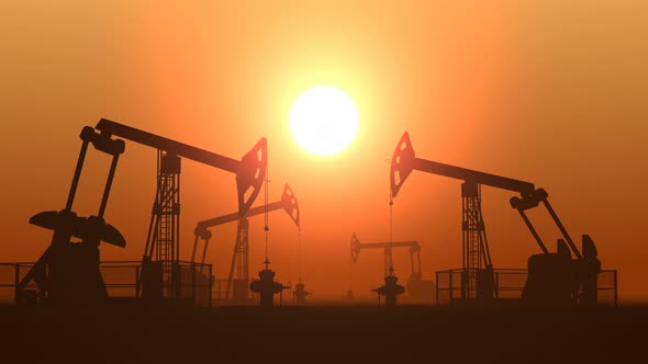 Working Oil Pump Jacks in a Desert against Sunset Extracting Crude Oil