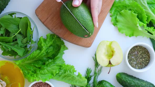 Woman Cooking Salad of Fresh Green Vegetables and Herbs