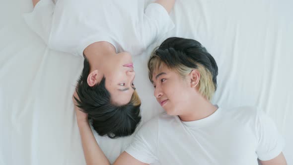 Asian young male gay lying down on bed and look at each other after wake up in morning in bedroom.