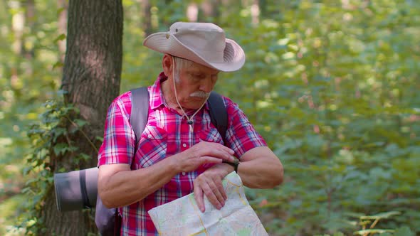 Senior Old Tourist Grandfather Man Lost and Looking at Map and Compass While Having Walk in Wood