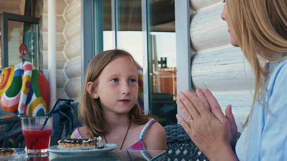 A Pretty Woman and a Girl are Sitting in a Cafe on the Terrace with Mirrorclear Windows