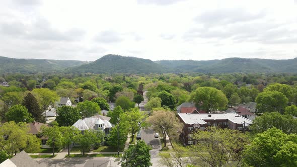 View down residential street in a midwest town toward tree covered mountains in the distance.