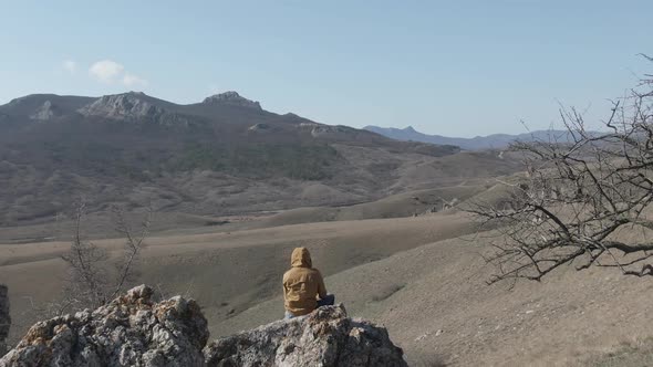 Man Sitting on the Big Stone and Enjoy the Scenery of the Mountain Range