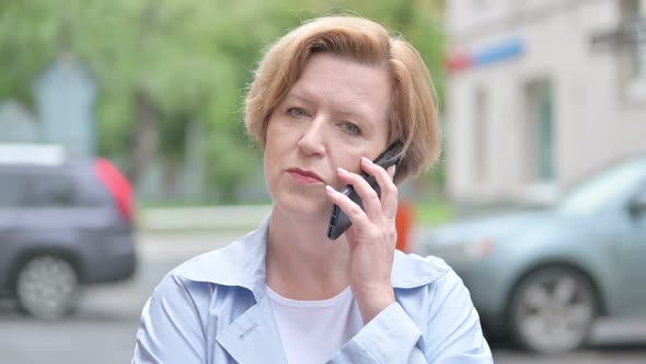 Old Woman Talking on Smartphone Standing Outdoor