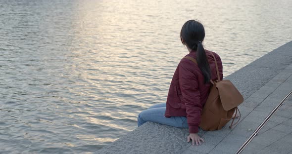 Woman enjoy the sunset view and sit besides the river