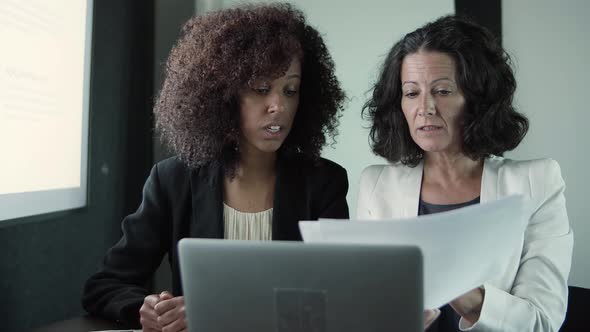 Two Content Businesswomen Sitting Together and Reading Reports