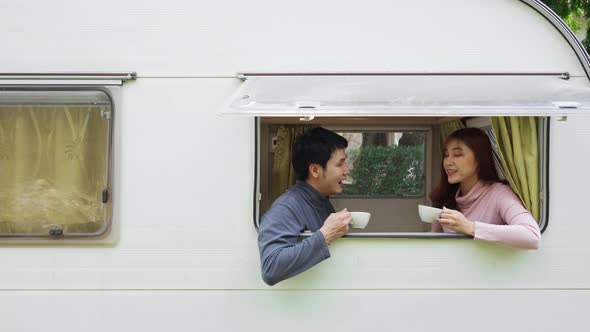 couple talking and drinking coffee at window of a camper RV van motorhome