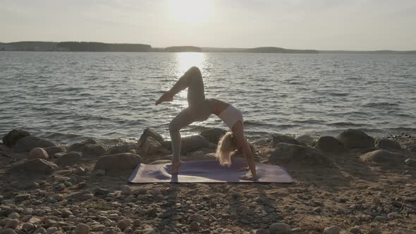 Young Athletic Beautiful Woman on the Background of the Sea. Fitness Girl Doing Exercises on the