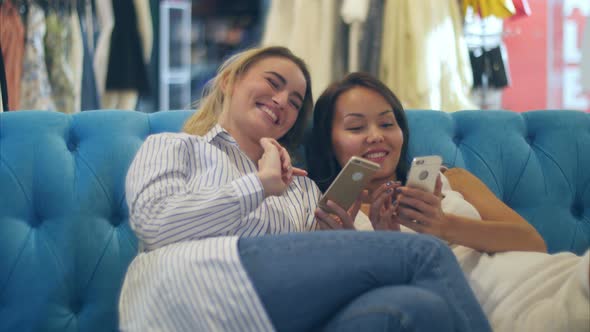 Happy Shopping Women Use Smartphone and Laugh Sitting in Mall