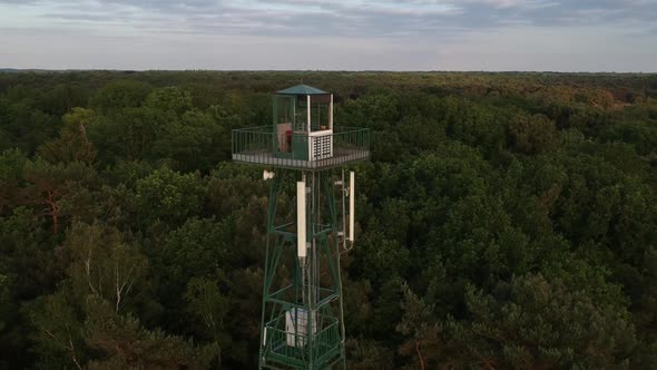 Push out aerial drone view of tall forest watchtower, evening time