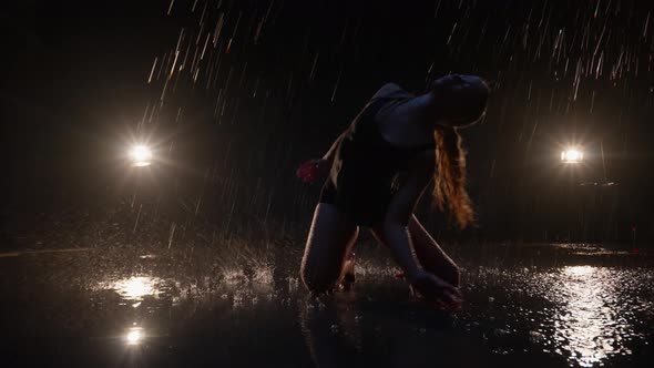 Sensual Young Woman Dancer Performing in the Rain in Dark Studio