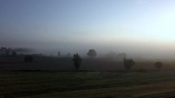 Tuscan countryside fields in Italy as sun rises on a cold foggy morning, Aerial dolly in reveal shot