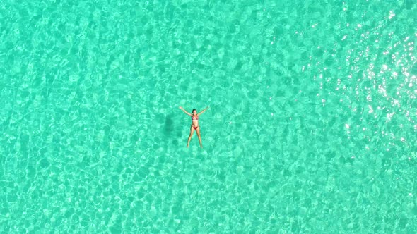 Aerial view of an attractive woman floating in crystal clear sea