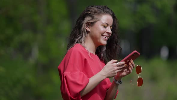 Woman is Sending Voice Message By Mobile Phone Walking in Park Positive Emotion and Good Mood