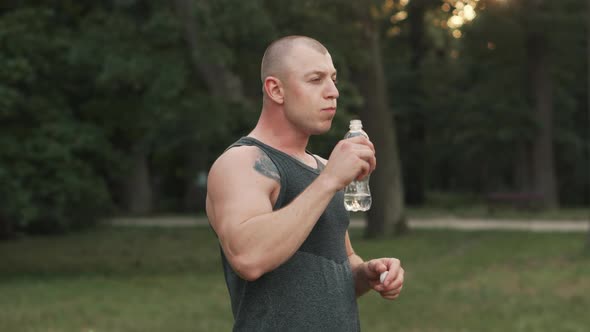 Sports Couple Drinking Water After Workout in Park