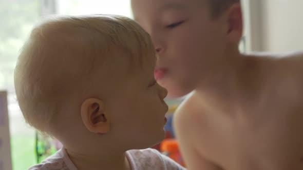Brother giving his baby sister a kiss at home