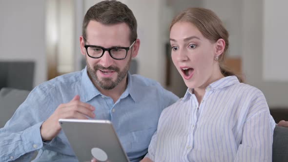 Portrait of Excited Young Couple Celebrating Success on Tablet