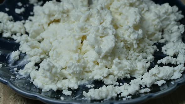 Spoon Stirs Milk Curd and Sour Cream in a Blue Bowl