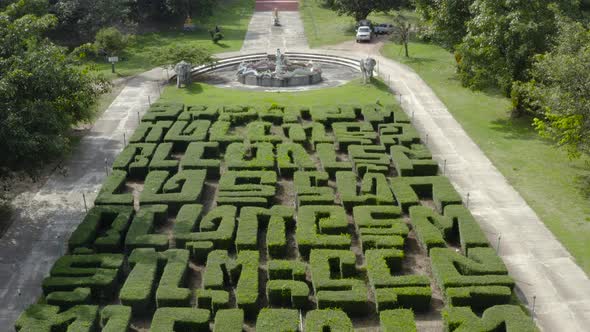 A beautiful drone shot rising from bushes spelling phrases in thai, to the stairs that lead to a tem