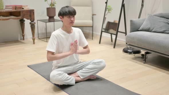 Young Asian Man Meditating on Yoga Mat at Home