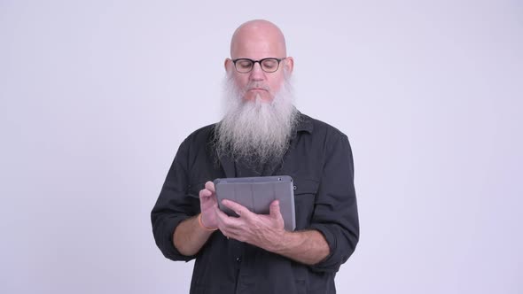 Mature Bald Bearded Man Using Digital Tablet