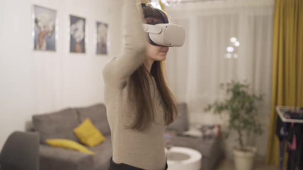 Smiling Girl Having Fun Using Joystick with Headset Goggles Touching Air During Visual Reality