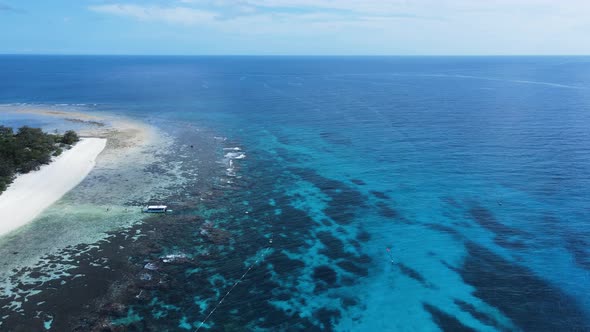 High view across a underwater reef system towards a group of boats moored in the tropical blue Islan