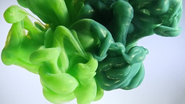 Green color paint drops in water against white background alt