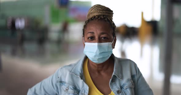 Mature african woman looking on camera while wearing safety face mask for coronavirus outbreak