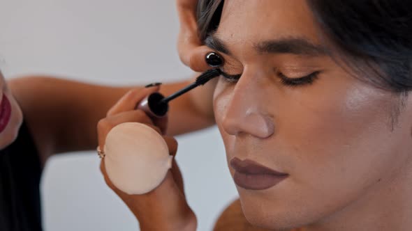 Make Up Artist Doing a Nude Bold Lips Look on Her Male Model - Applying Mascara on His Eyelashes