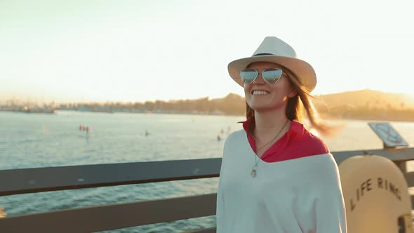 Happy Attractive Woman Walking By Pier, Enjoying Summer Sunset with Water View