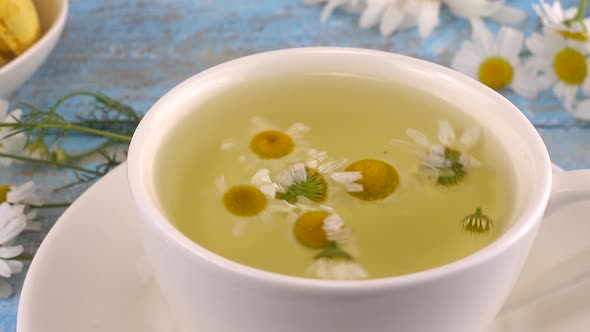 Brewing a herbal tea from chamomile in white cup. Summer theme.