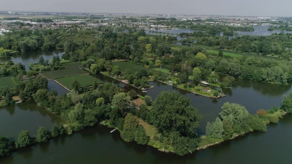 Aerial Slomo Wide shot of Dutch Countryside surrounded with Small Rivers, Green Trees and Bushes, ti