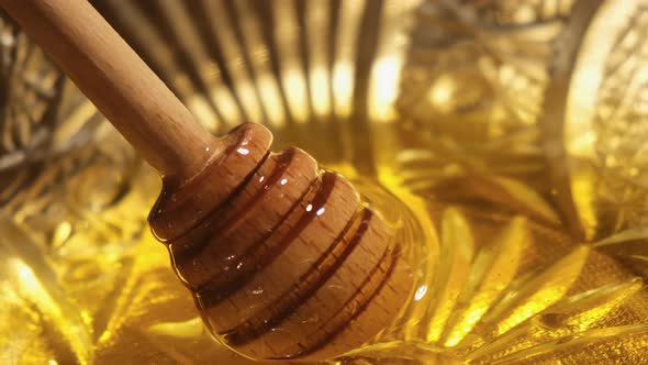 Wooden Honey Dipper Dipping in Glass Bowl Full of Honey