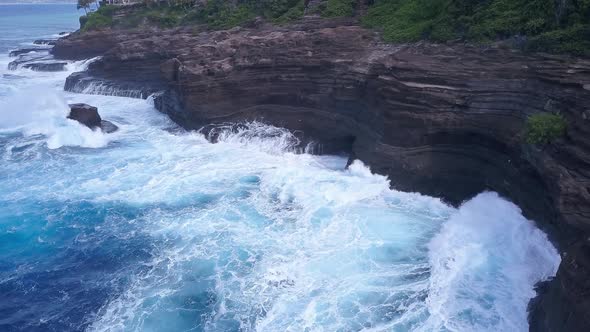 Aerial view of spitting cave against crashing ocean waves in Oahu