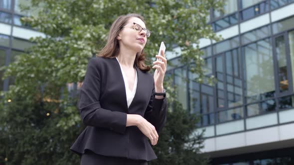 Smiling Businesswoman Browsing Smartphone Near Office Building