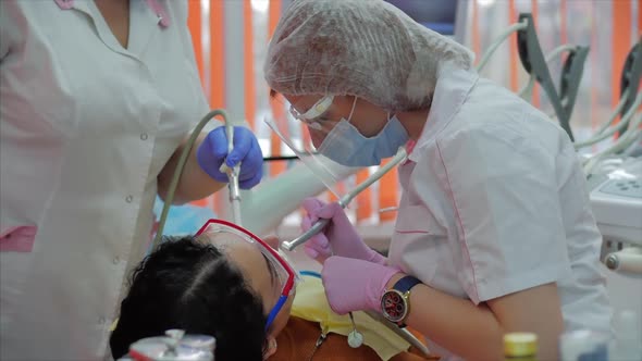 Woman Dentist Treating Teeth To Woman Patient in Clinic. Female Professional Doctor Stomatologist at